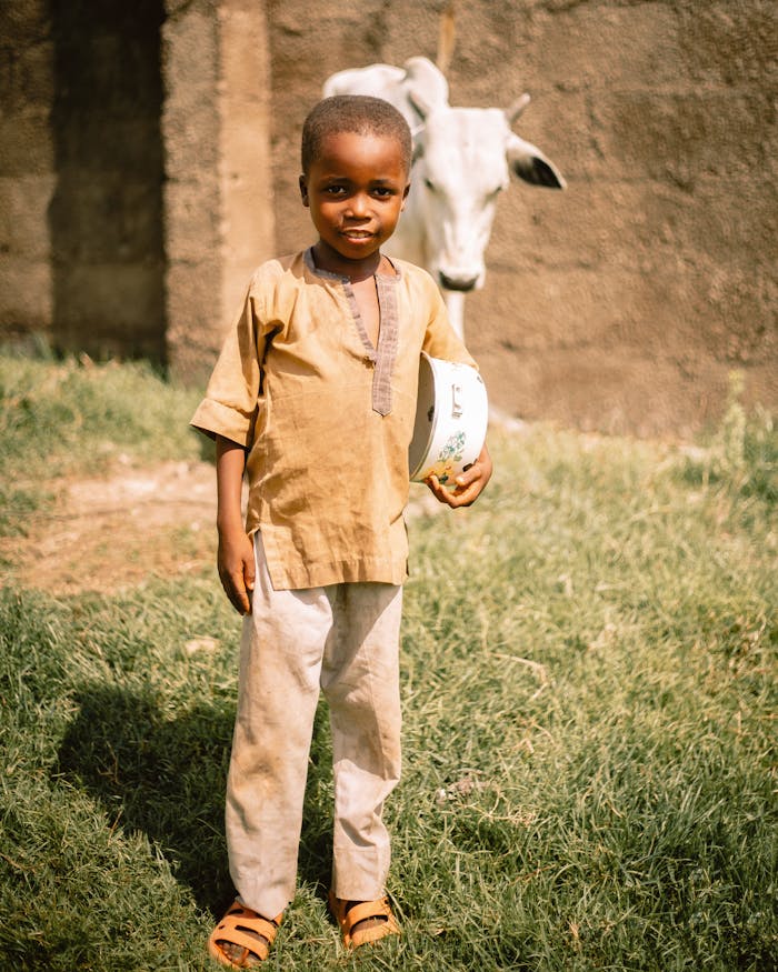 services-01 Young child holding a bowl outdoors in Kaduna, Nigeria, showcasing local life.