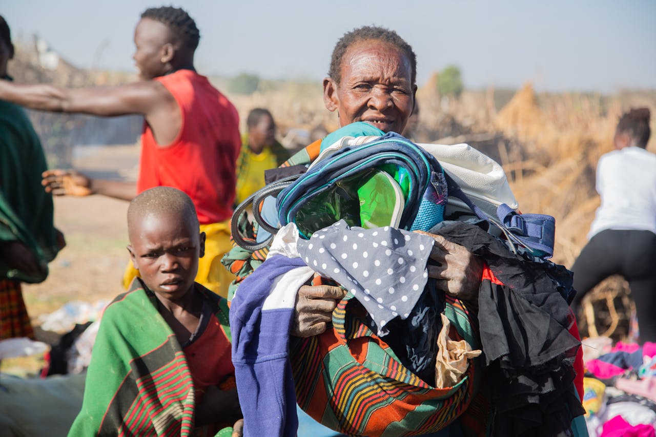 A group of African individuals exchanging clothes in an outdoor setting, reflecting community support.