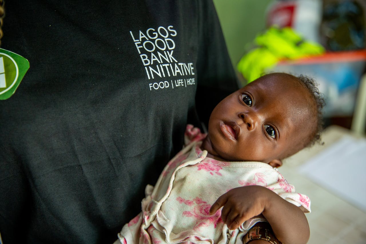 services-02 A compassionate volunteer holds a baby at the Lagos Food Bank to support vulnerable children.